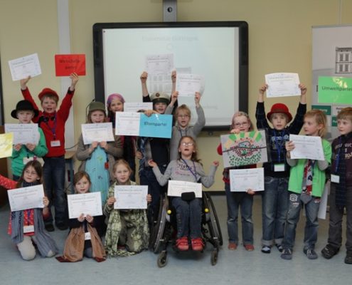 Gruppe von Kindern, die Plakate zum Planspiel hochhalten